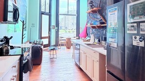 Una cocina con piso de madera, ventilador de techo y vista a través de un gran ventanal.