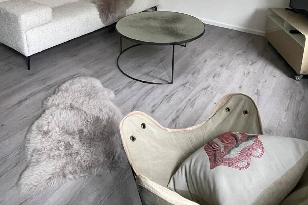 Un dormitorio tipo loft moderno con techo inclinado, un sofá, una mesa redonda de centro y una silla.