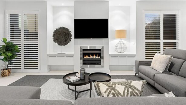 A modern living room with a fireplace, a flat-screen TV, and a sofa. - Beach house on a golf course (Torquay)