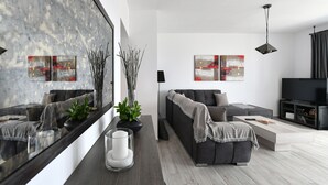 A modern living room with a sofa, coffee table, and artwork on the walls. - Parikia's Seaside House (Paros)