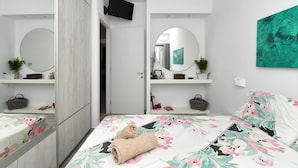 A bedroom with a bed, a mirror, a television, and a painting. - Parikia's Seaside House (Paros)