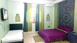 Ein Schlafzimmer mit Bett, Fernseher, Kommode und einer Wandverkleidung.