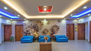 A lobby with blue sofas, a wooden coffee table, and decorative wall art. - HOTEL PUSHPO BILASH (Khulna)