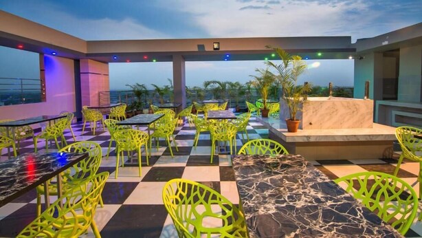 A rooftop terrace with checkered flooring, green metal chairs, and a marble table. - HOTEL PUSHPO BILASH (Khulna)