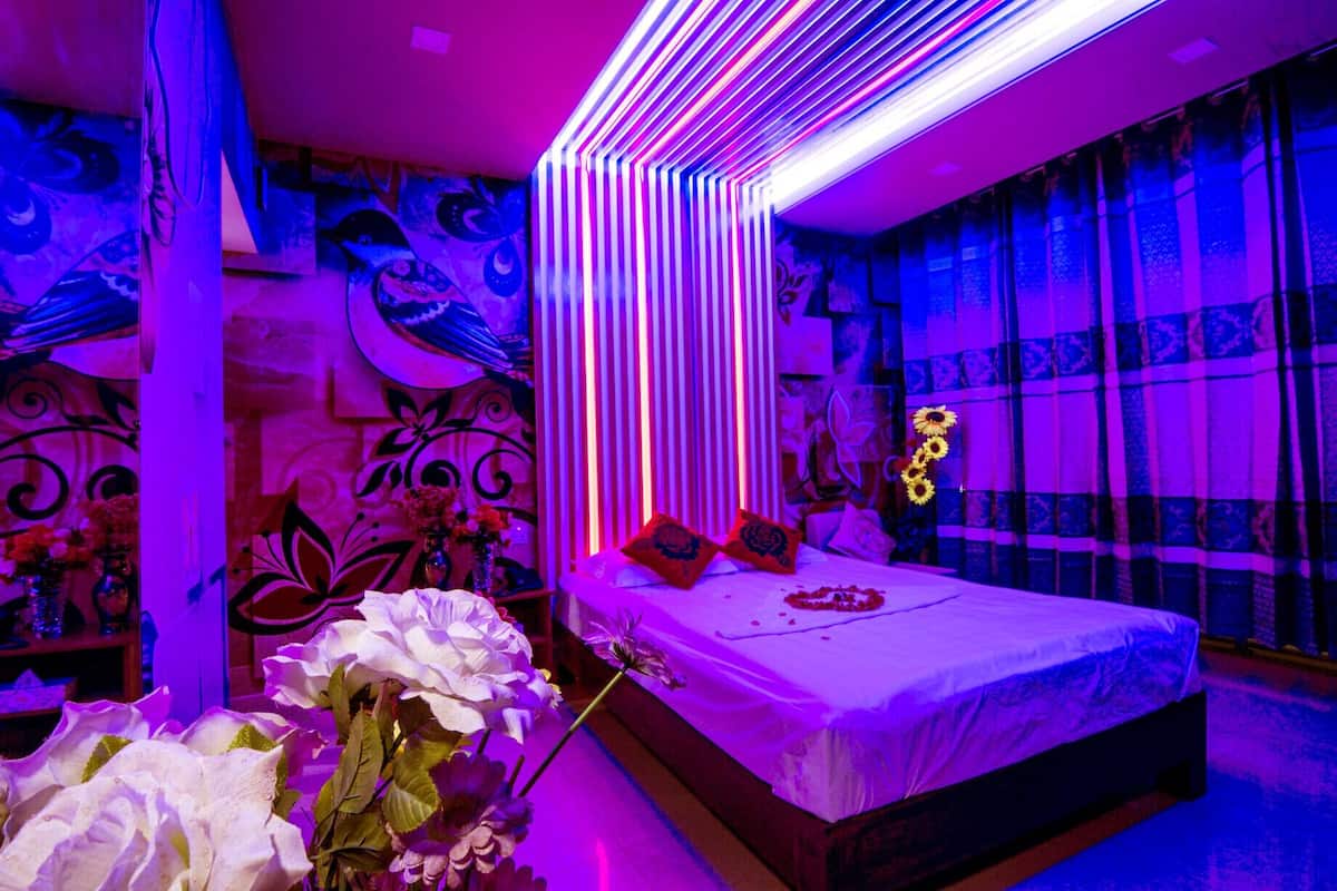 A modern bedroom with a large bed, decorative pillows, and a vase of flowers.