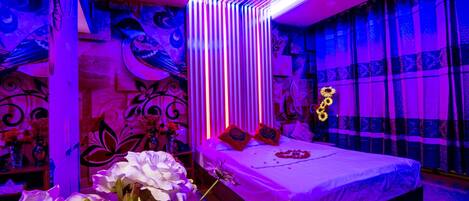 Une chambre moderne avec un grand lit, des coussins décoratifs et un vase de fleurs.