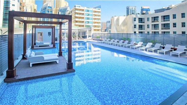 A rooftop pool with lounge chairs and a pergola. - Stunning Apt Marina view with Balcony (Dubai)