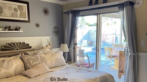 A bedroom with a large bed, a bench, a ceiling fan, and a view of an outdoor patio. - Staycation Home minutes to all Pheonix has to offer (Glendale)