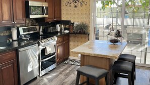 A modern kitchen with dark wood cabinets, stainless steel appliances, a granite countertop, and a bar area with stools. - Staycation Home minutes to all Pheonix has to offer (Glendale)