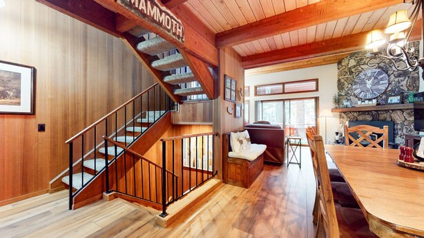 Un interior de madera con una escalera, un comedor y una chimenea de piedra.