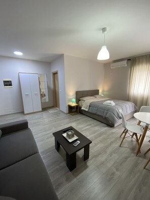 A modern hotel room with a bed, a sofa, a small table, and a desk with a chair. - Captivating 1-bed Apartment in Vlore (Vlorë)