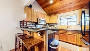 A kitchen with wooden cabinets, a microwave, a refrigerator, and a sink. - Woodlands #11 3 Bedroom Condo by RedAwning (Mammoth Lakes)