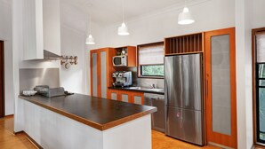 Uma cozinha moderna com ilha central, eletrodomésticos de aço inoxidável, armários de madeira e iluminação pendente.