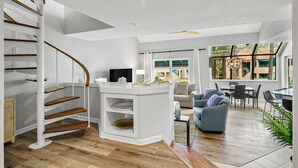 A modern interior with a white staircase, a kitchen area, a dining space, and a view of the outside. - Updated 3 bedroom Villa in Shelter Cove with Community Pool (Hilton Head Island)
