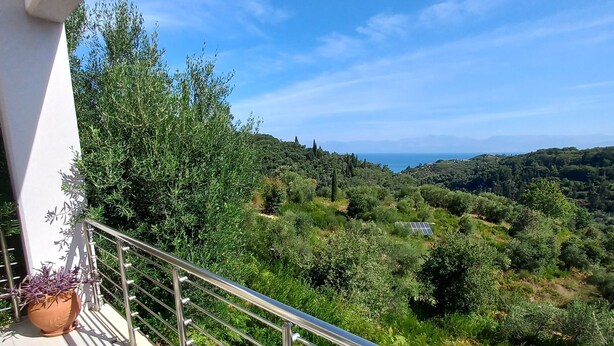 Un balcon offrant une vue sur un paysage verdoyant et des montagnes lointaines.