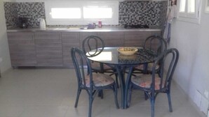 Une cuisine avec une table et des chaises, une fenêtre et un revêtement mural en carreaux.