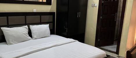 Une chambre à coucher avec un grand lit, une armoire et une porte donnant sur une autre pièce.