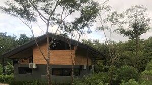 Una casa moderna con facciata in legno, circondata da rigogliosa vegetazione e alberi.