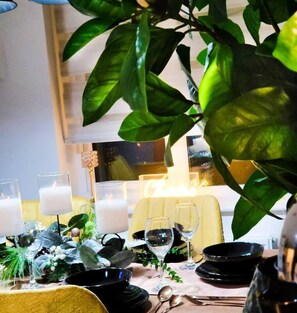 A dining table set with black bowls, wine glasses, and candles, surrounded by greenery and decorative elements. - Birmingham Airport Luxury3brhome (Birmingham)