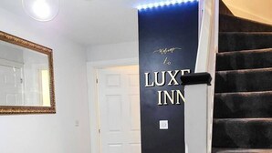 Ein Korridor mit einem schwarzen Schild, auf dem “LUXE INN” steht, und einem Spiegel an der Wand.
