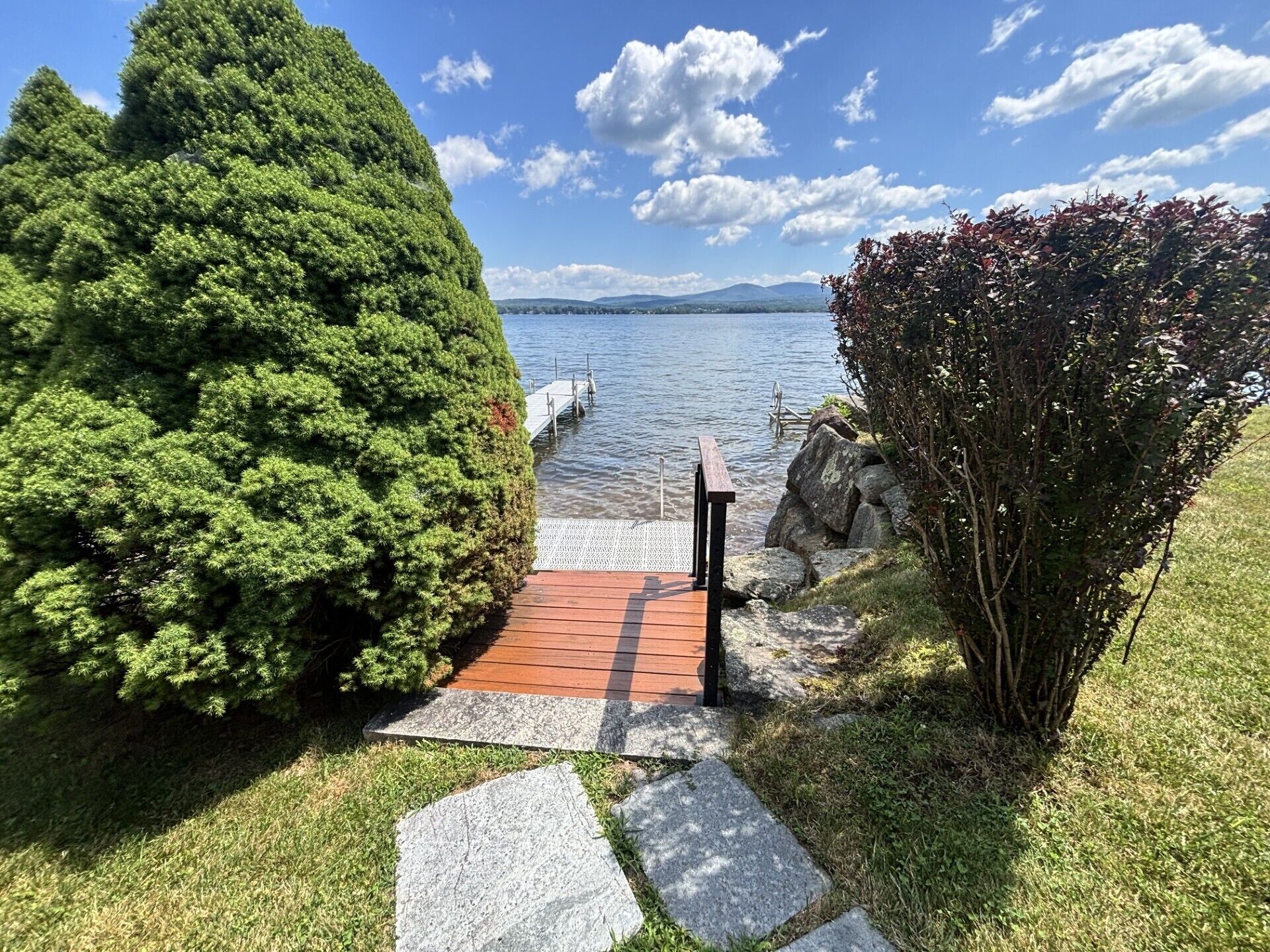 A wooden dock leading to a lake with a clear sky.