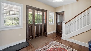 A hallway with wooden doors, a patterned rug, and a staircase with white railings.