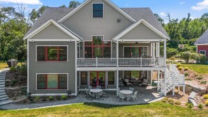 A two-story house with a balcony, a covered patio, and a stone staircase leading to the entrance.