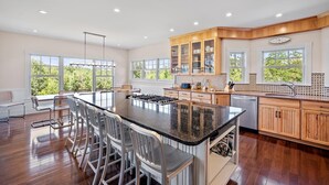 A spacious kitchen with a large island, wooden cabinets, and a view of greenery outside.