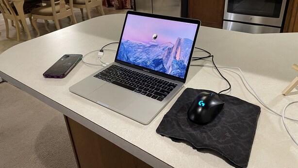 Ein Laptop auf einer Küchenarbeitsplatte, zusammen mit einer Maus und einem Telefon.
