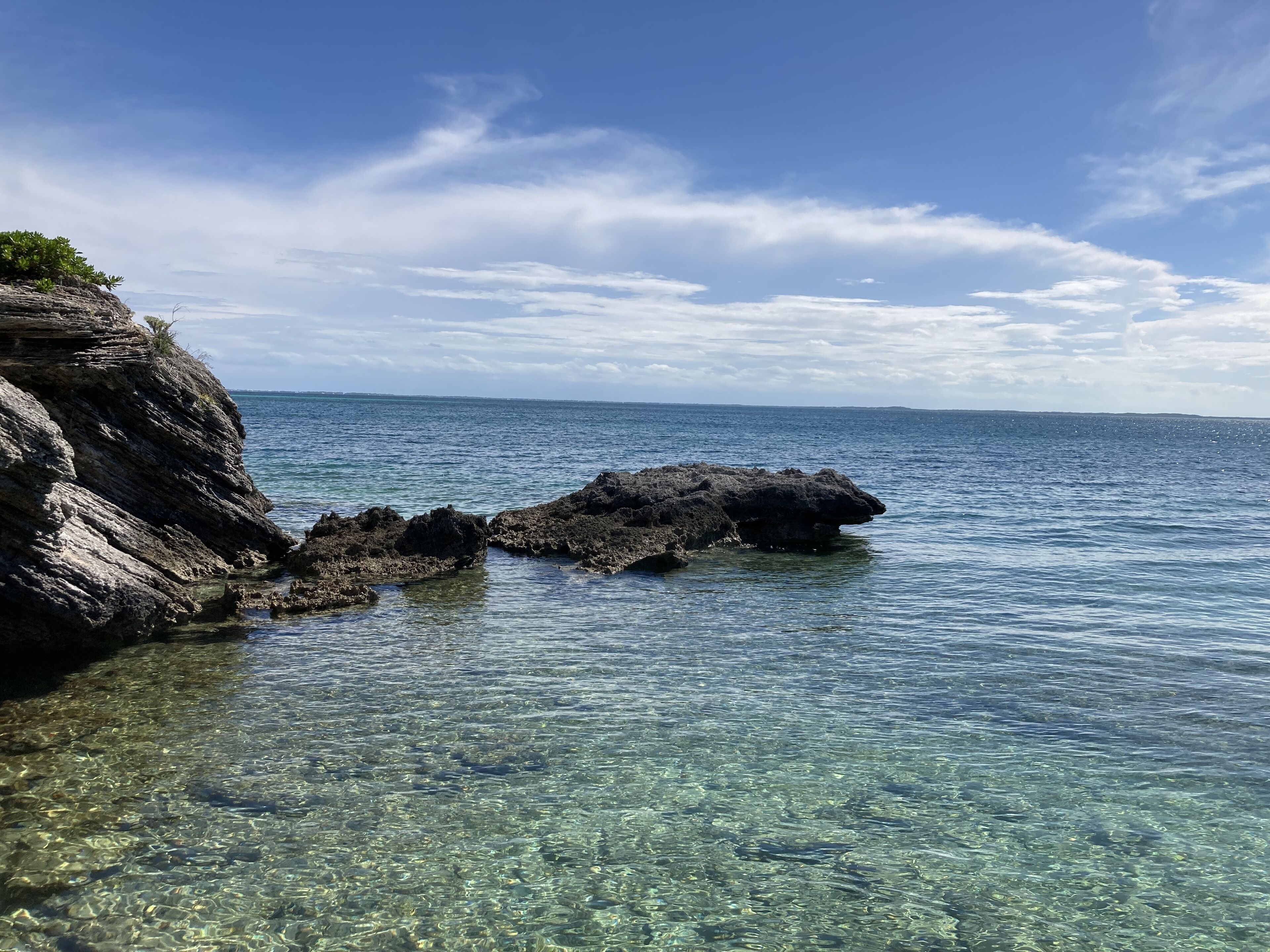 Eine Küstenlandschaft mit klarem Wasser, Felsformationen und einer entfernten Küste.