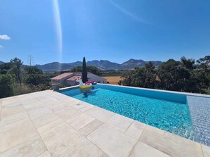 Una piscina con agua azul cristalina, rodeada por una solana con baldosas.