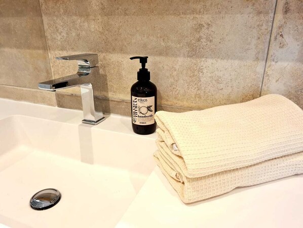 A bathroom sink with a black bottle of hand soap and a folded white towel.