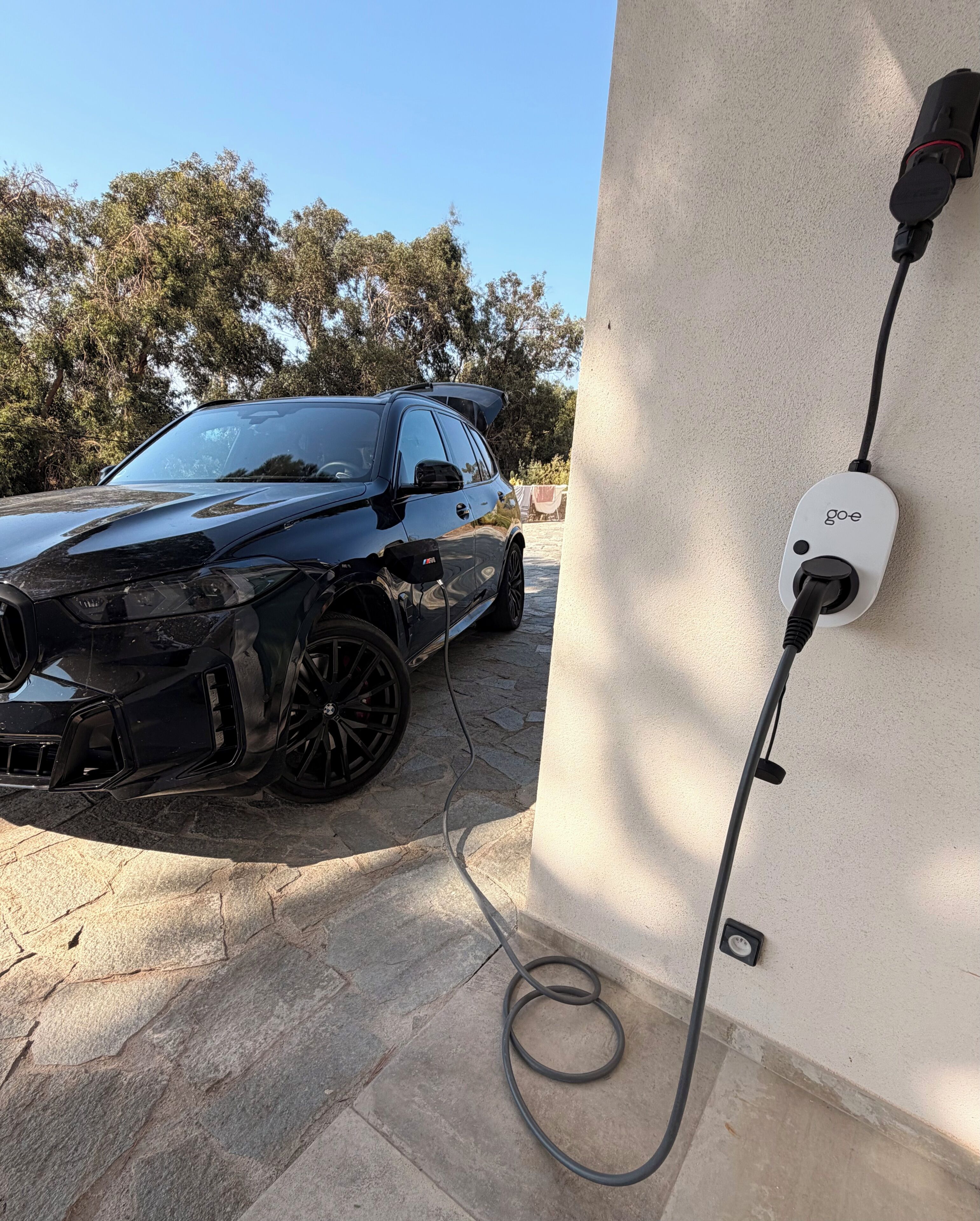 En sort bil parkeret ved en opladestation med en tilsluttet ledning.