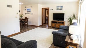 A living room with a sofa, TV, and a dining area with chairs and a table. - 2 E-Bikes & Kayaks included & No Cleaning Fees!! (Clear Lake)