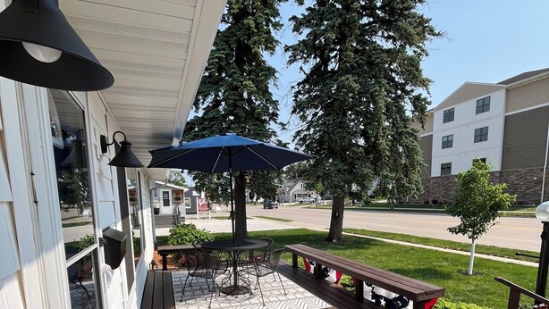 A wooden deck with a table and chairs, a blue umbrella, and a bench with flags. - 2 E-Bikes & Kayaks included & No Cleaning Fees!! (Clear Lake)