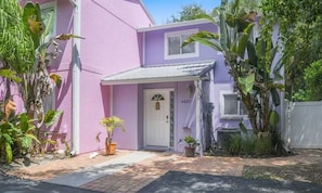 Un bâtiment rose avec une porte blanche portant l’inscription « 4025 » et un petit porche.