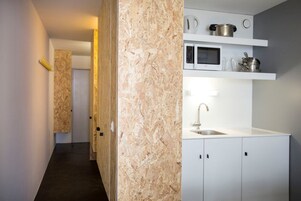 Una cocina moderna con armarios blancos, un lavamanos de acero inoxidable y un microondas.