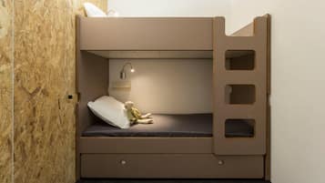 Un lit superposé avec une tête de lit, une lampe de chevet et une petite étagère.