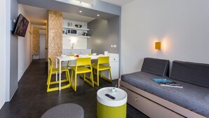 A modern, compact living space with a kitchenette, a dining area with yellow chairs, and a grey sofa. - Résidence Le Varet (Bourg-Saint-Maurice)