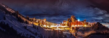 Une montagne enneigée, sur laquelle se trouve une station de ski comprenant plusieurs bâtiments et un télésiège.