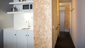 A modern kitchen with white cabinetry, a stainless steel sink, and a microwave. - Résidence Le Varet (Bourg-Saint-Maurice)