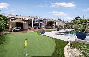 A golf course with a putting green, a pool, and outdoor seating areas.