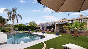 A pool area with artificial grass, lounge chairs, and a covered patio with string lights. - Large House in Lake La Quinta Community. Gated with Security Guard, Private Pool (La Quinta)