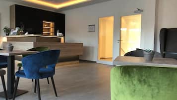 Un área de recepción moderna con un mostrador de madera, una silla azul y una silla verde.