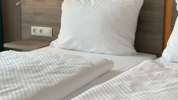 Une chambre d’hôtel avec deux lits, une table de chevet, une lampe et une prise de courant.
