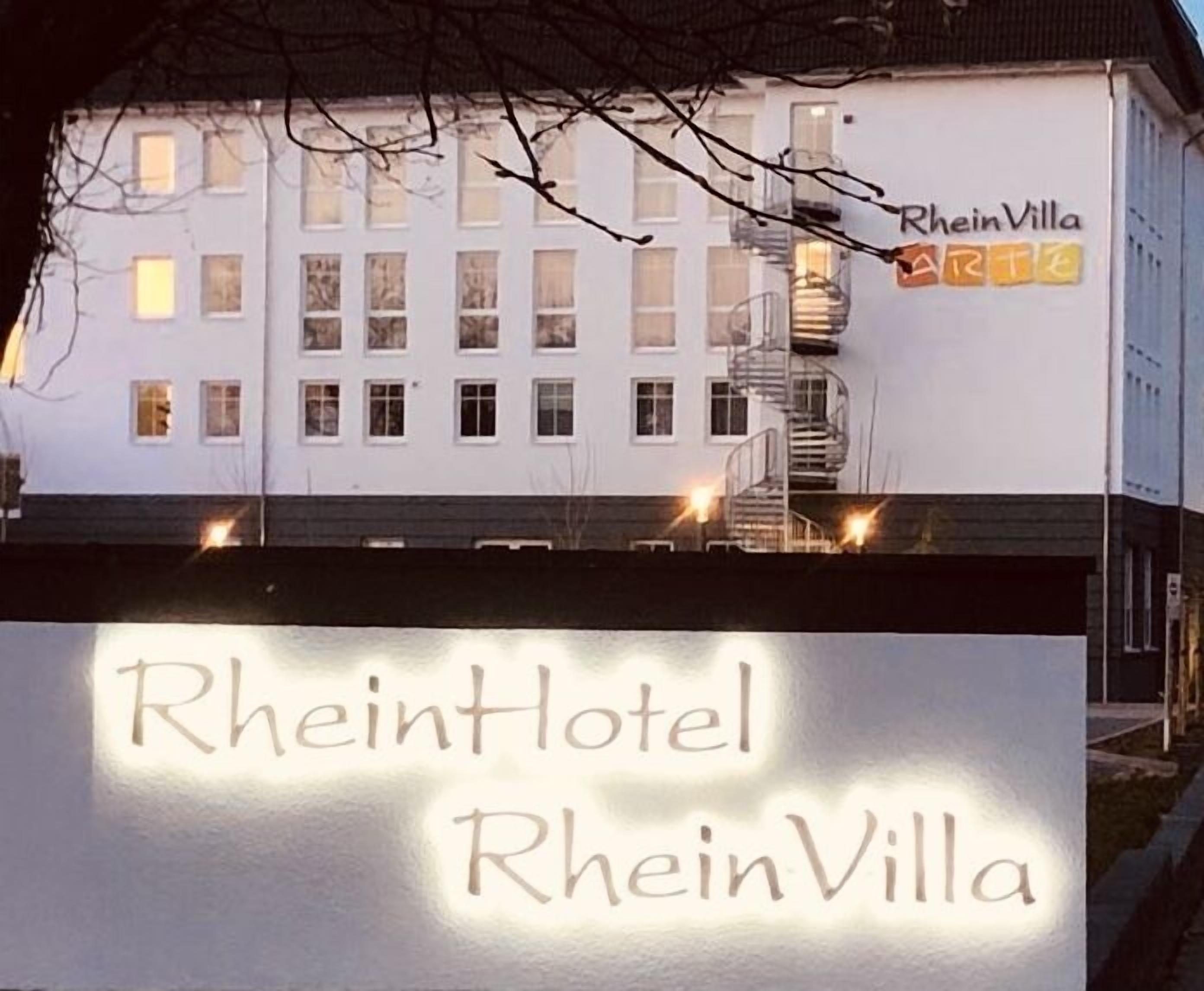 Segnaletica di un hotel con il nome "RheinHotel RheinVilla" e un edificio con diverse finestre e una scala.