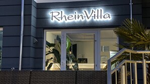 The exterior of RheinVilla with a modern design, featuring a prominent illuminated sign and a glass entrance. - RheinVilla ARTE (Remagen)