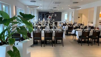 A modern restaurant with multiple dining tables and chairs, large windows, and a clean, minimalist interior design.