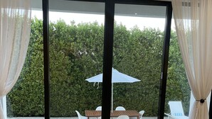 A room with a large sliding glass door leading to an outdoor area with a pool, a table, and chairs. - The White House TCI Guest House (Providenciales)
