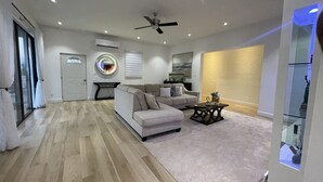 A modern living room with a sofa, coffee table, and a ceiling fan. - The White House TCI Guest House (Providenciales)